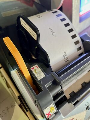 A Brother QL550 label printer with its cover open, showing the handle used to change label rolls